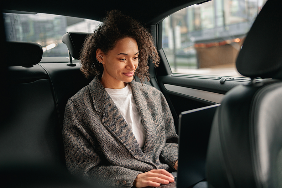Female at the back seat of the car on the laptop